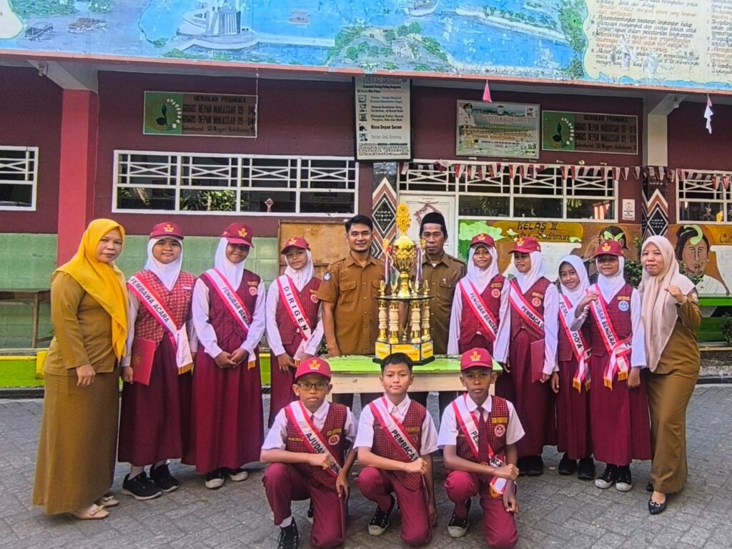 Sejumlah siswa berseragam merah putih bersama guru SDN Kalukuang 2 berfoto di halaman sekolah dengan piala di tengah sebagai simbol kesiapan mengikuti program Tahsin Tahfidz Al-Qur’an di Makassar.